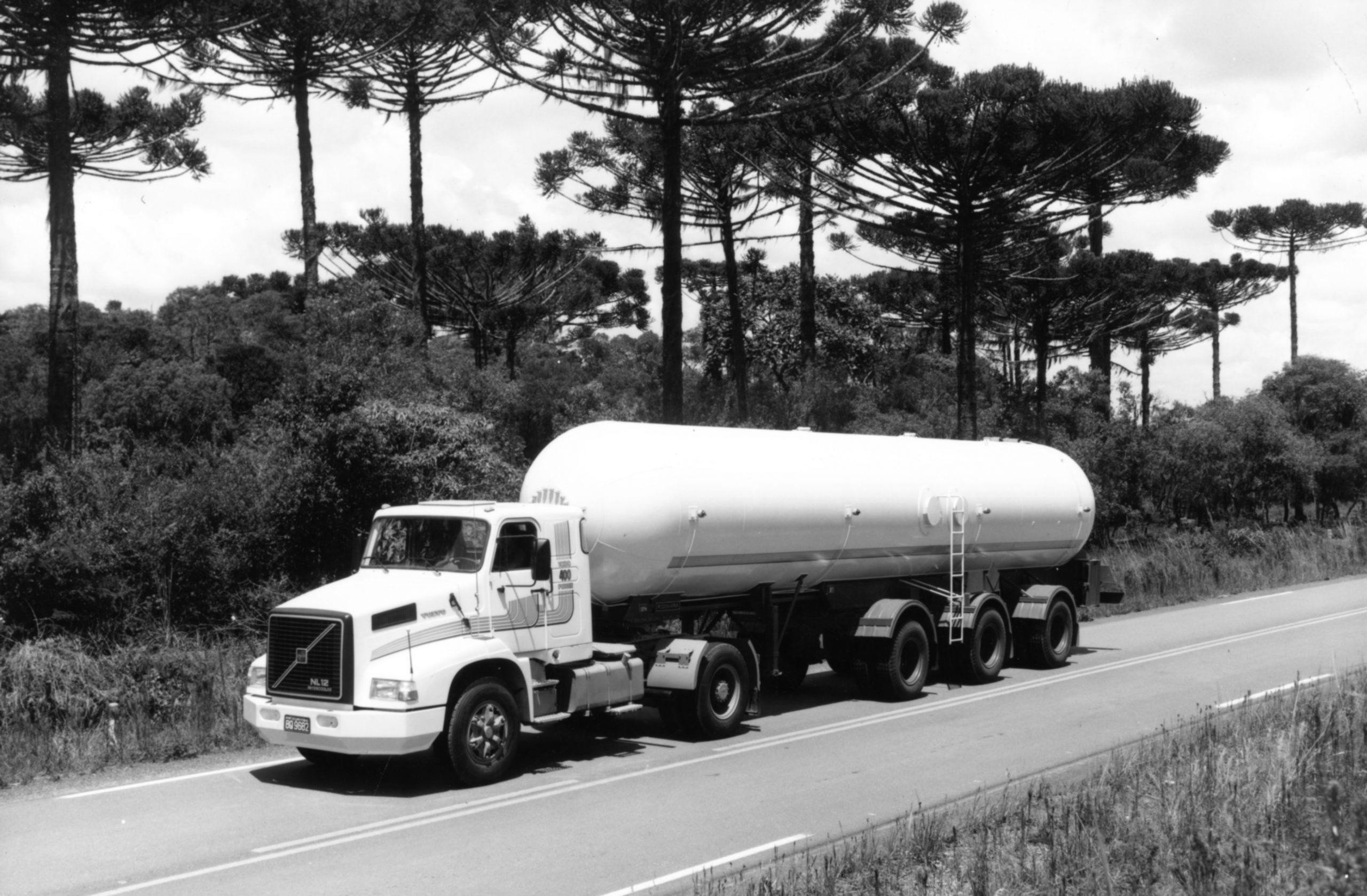 Modelo caminhão tanque com semirreboque de três eixos em via asfaltada.